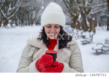 Woman Enjoying Hot Drink in Snowy Park 136797711