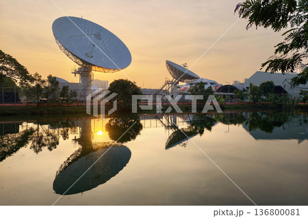 Satellite dish antenna station with reflection on pond at sunrise Satellite dish antenna station with reflection on pond at sunrise 136800081