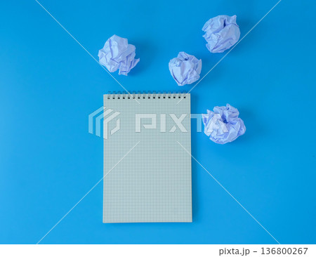 A crumpled sheet of paper with blank booknote on blue background. 136800267