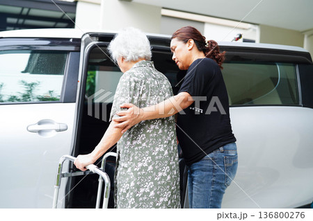 Caregiver help Asian elderly woman disability patient get in her car. Caregiver help Asian elderly woman disability patient get in her car. 136800276