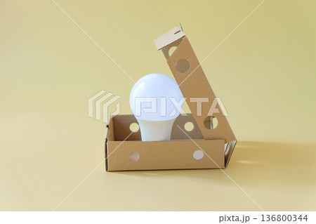 Light bulb in cardboard box on color background. Light bulb in cardboard box on color background. 136800344