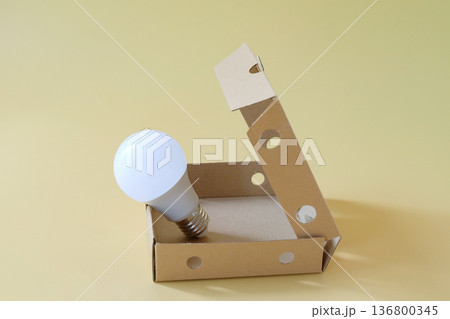 Light bulb in cardboard box on color background. Light bulb in cardboard box on color background. 136800345