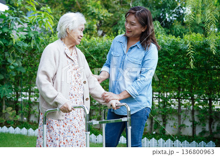 Caregiver help Asian elderly woman disability patient walk with walker in park, medical concept. 136800963