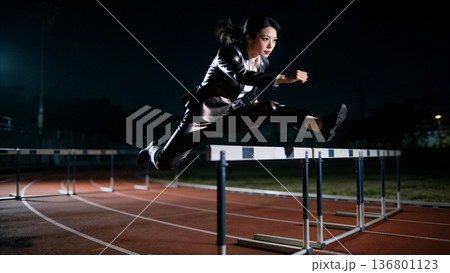 ハードルを越えるスーツの女性と正面から走る姿 ビジネスの課題解決と挑戦 陸上トラック 成功 躍動感 136801123