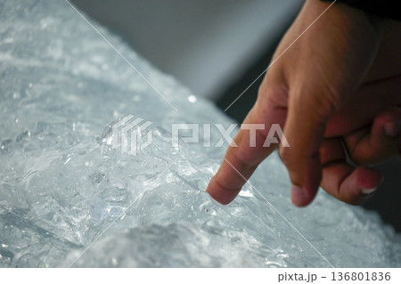 Finger of human hand touching piece of ice fallen from the spegazzini glacier los glaciares park argentina 136801836