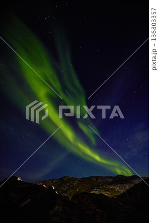 Aurora borealis over ocean in Teriberka, Russia, Murmansk region, Northern lights, Starry sky with polar lights and clouds. Night autumn landscape with bright aurora, stars, sea 136803357