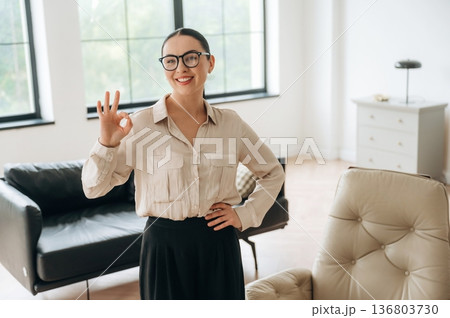 Okay hand sign. Woman in formal clothes is in the modern big room 136803730