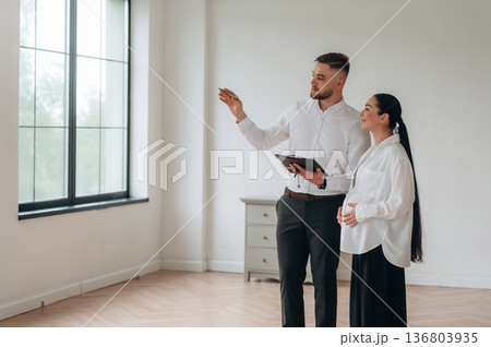 Realtor is showing the interior. Man and woman are in the modern new room, conception of business 136803935