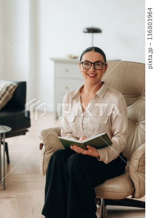 In glasses, front view. Woman in formal clothes is in the modern big room In glasses, front view. Woman in formal clothes is in the modern big room 136803964