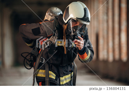 Standing in the abandoned building. Firefighter in professional equipment is indoors Standing in the abandoned building. Firefighter in professional equipment is indoors 136804131