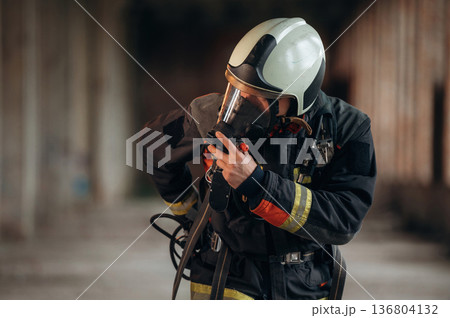 Standing in the abandoned building. Firefighter in professional equipment is indoors Standing in the abandoned building. Firefighter in professional equipment is indoors 136804132