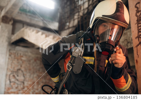 Firefighter in professional equipment is indoors in abandoned building Firefighter in professional equipment is indoors in abandoned building 136804185