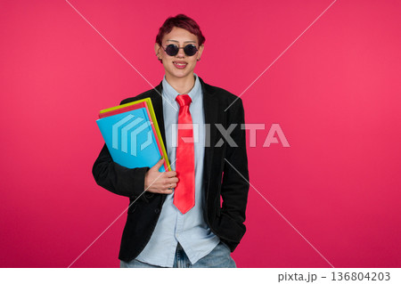Confident young person holding folders smiling at camera 136804203