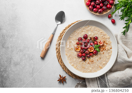 Oatmeal with cranberry, cinnamon and spicy in a plate on a gray concrete background Oatmeal with cranberry, cinnamon and spicy in a plate on a gray concrete background 136804250