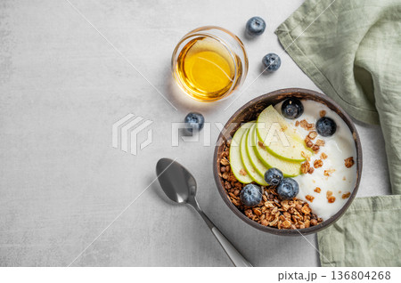 Natural greek yogurt with granola, blueberry and apple in a bowl on a light background with honey 136804268