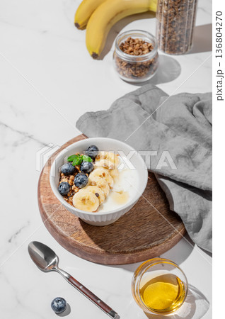 Greek yogurt with granola, blueberry and banana in a bowl on a wooden board Greek yogurt with granola, blueberry and banana in a bowl on a wooden board 136804270