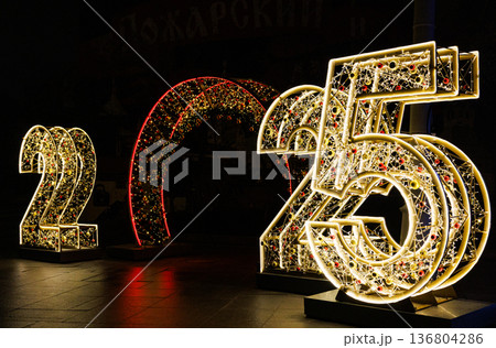 Sparkling lights display announcing the year 2025 in a festive nighttime setting Sparkling lights display announcing the year 2025 in a festive nighttime setting 136804286
