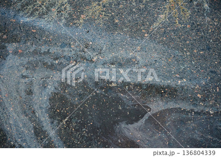 Iridescent oil slick creating colorful patterns on dark urban asphalt 136804339