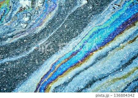 Iridescent oil slick creating abstract rainbow pattern on asphalt. Iridescent oil slick creating abstract rainbow pattern on asphalt. 136804342