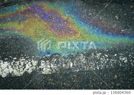 Oil spill creating a colorful rainbow pattern on wet dark asphalt with a white line. Oil spill creating a colorful rainbow pattern on wet dark asphalt with a white line. 136804360