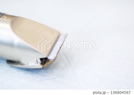 Close view of professional hair clipper resting on wellkept fabric surface in natural light Close view of professional hair clipper resting on wellkept fabric surface in natural light 136804567
