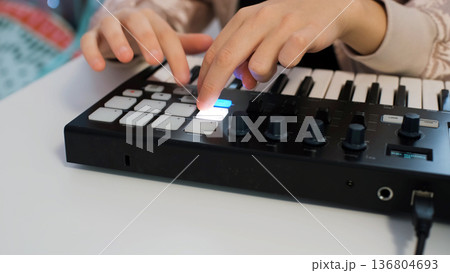 Close-up of teen girl enjoys making music at home with midi keyboard while wearing headphones and sunglasses, expressing her creativity 136804693