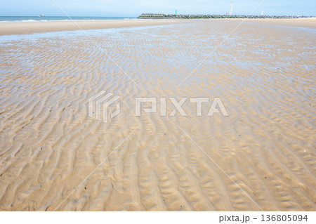 Beautiful sea with sand, waves, yachts, waves on the water and blue sky. Natural background. Summer vacation in Ostend, Belgium. Beautiful sea with sand, waves, yachts, waves on the water and blue sky. Natural background. Summer vacation in Ostend, Belgium. 136805094