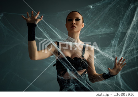 Powerful woman with dramatic black eye makeup trapped in a spooky spiderweb Powerful woman with dramatic black eye makeup trapped in a spooky spiderweb 136805916