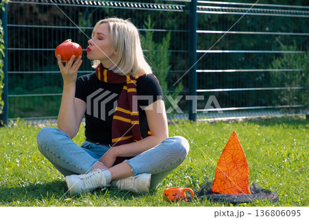 A beautiful girl is sitting on the terrace with a dog, holding a pumpkin in her hand. A beautiful girl is sitting on the terrace with a dog, holding a pumpkin in her hand. 136806095