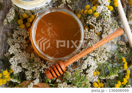 fresh natual honey in glass jar with wooden honey spoons around herb flowers. macro fresh natual honey in glass jar with wooden honey spoons around herb flowers. macro 136806099