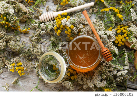 fresh natual honey in glass jar with wooden  honey spoons around herb flowers. flat lay 136806102