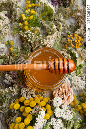 fresh natual honey in glass jar with wooden  honey spoons around herb flowers. macro 136806105