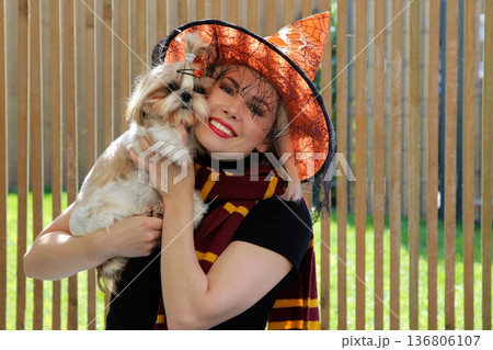 A beautiful girl is sitting on the terrace with a dog, holding a pumpkin in her hand. A beautiful girl is sitting on the terrace with a dog, holding a pumpkin in her hand. 136806107