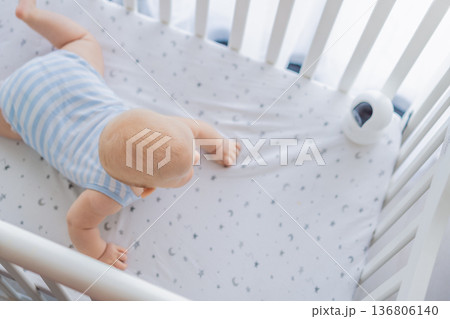 Baby monitor camera placed inside a crib where an infant is lying, ensuring safety and constant supervision. Modern parenting scene combining care and technology. Baby monitoring, security and smart Baby monitor camera placed inside a crib where an infant is lying, ensuring safety and constant supervision. Modern parenting scene combining care and technology. Baby monitoring, security and smart 136806140