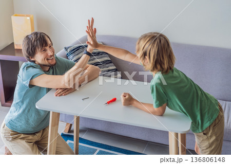 Father and his son assembling a table together in the living room at home. Meaningful family moment showing teamwork, learning and support. Fatherhood, home improvement and bonding through shared Father and his son assembling a table together in the living room at home. Meaningful family moment showing teamwork, learning and support. Fatherhood, home improvement and bonding through shared 136806148