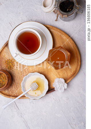 linden honey with perga and cup of tea at wooden tray on white table.  flat lay 136806185