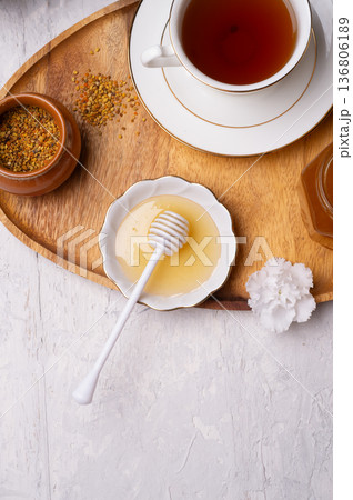 linden honey with perga and cup of tea at wooden tray on white table. top view linden honey with perga and cup of tea at wooden tray on white table. top view 136806189