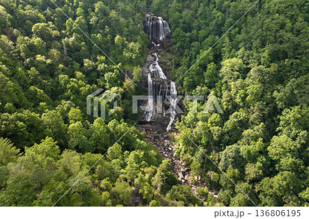 Beautiful landscape of high waterfall with falling down clear water from rocky boulders between green lush woods. Whitewater Falls in Nantahala National Forest, North Carolina, USA Beautiful landscape of high waterfall with falling down clear water from rocky boulders between green lush woods. Whitewater Falls in Nantahala National Forest, North Carolina, USA 136806195