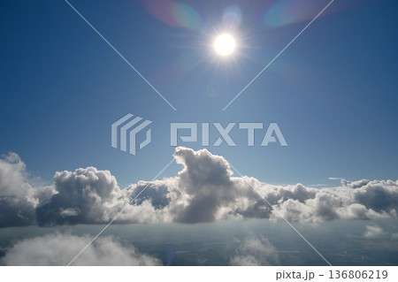 Aerial view from airplane window at high altitude of earth covered with white puffy cumulus clouds Aerial view from airplane window at high altitude of earth covered with white puffy cumulus clouds 136806219