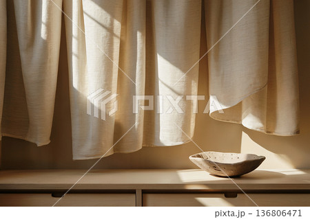 Sunlight on linen curtains with ceramic bowl in minimalist interior 136806471