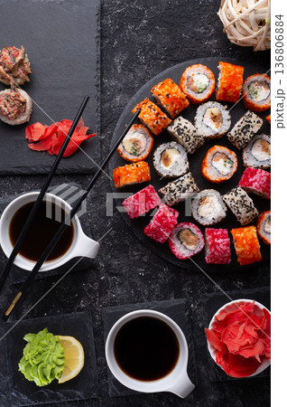 different sushi rolls set  with fish and  shiitake mushrooms  served  at black dishes at black table. flat lay 136806884