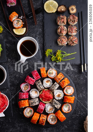 different sushi rolls set with fish and  shiitake mushrooms  beautiful served  at black dishes at black table. flat lay 136806889