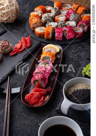 different sushi rolls set  with fish  served  at black dish at black table. 136806896