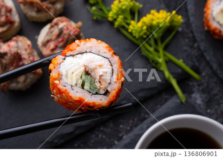 sushi roll in chopsticks and  shiitake mushrooms  beautiful served  at black dish. top view. macro shot 136806901