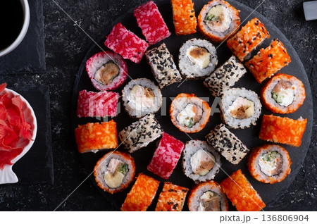 different delicious sushi rolls set with fish served at black dish at black table. flat lay. close up different delicious sushi rolls set with fish served at black dish at black table. flat lay. close up 136806904
