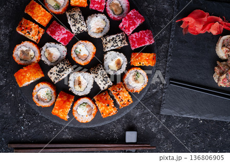 different delicious sushi rolls set with fish beautiful served at black dish at black table. flat lay. close up different delicious sushi rolls set with fish beautiful served at black dish at black table. flat lay. close up 136806905