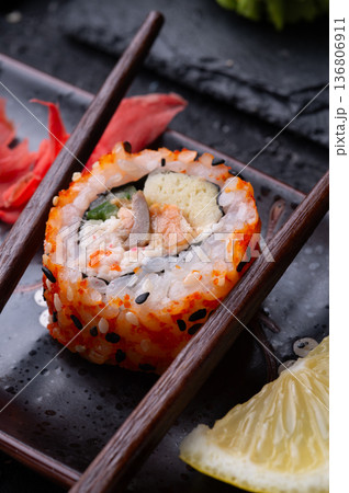 sushi roll in chopsticks beautiful served  at black dish. top view. macro shot 136806911