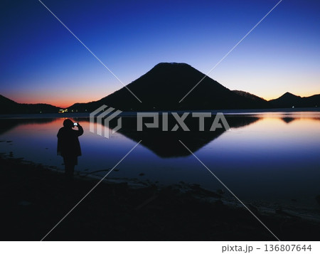 夜明けの湖のほとりに立つ人（20260212055327） 136807644