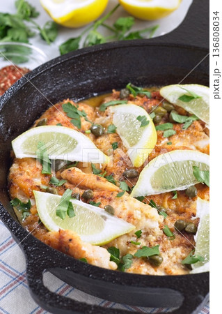 Delicious haddock fish piccata with lemon and capers in cast iron pan, vertical 136808034