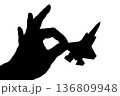 指でつままれたシルエットのジェット戦闘機 136809948